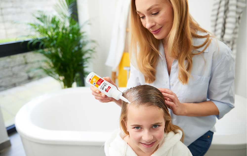 Haarbeandlung mit mosquito Läuseprodukten Ein Mädchen bekommt Ihre Haare mit mosquito Läuseprodukten von Ihrer Mutter behandelt